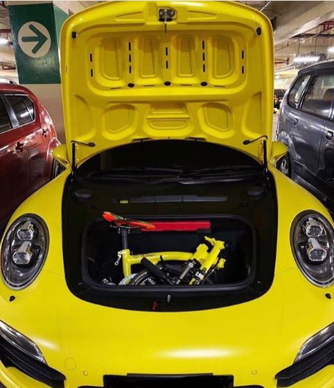 Image of a folded yellow Brompton packed in the front trunk of a yellow car