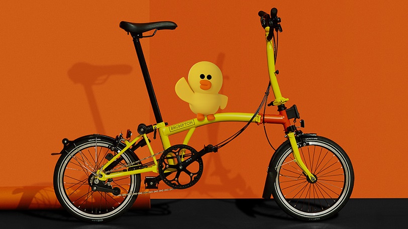 The Sally special edition yellow Brompton bike with a rubber duck on orange background