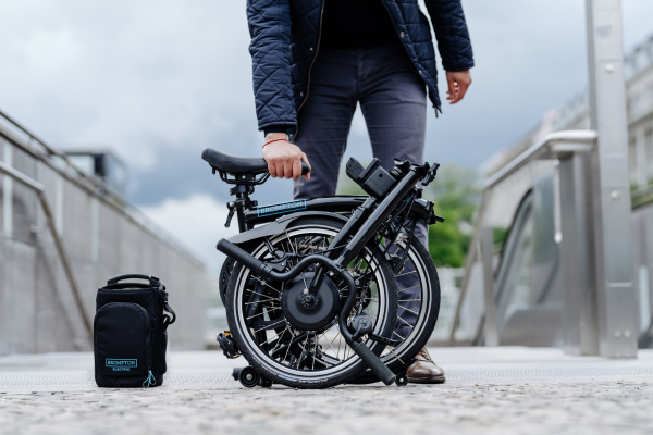Image of person holding the seat of a folded electric Brompton bike