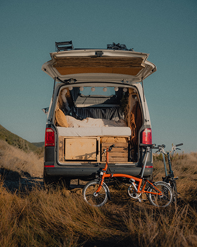 A Brompton leans against a van with the back door open.