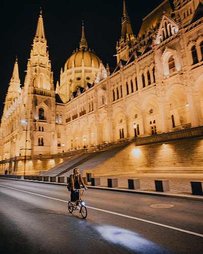Lennart's girlfriend drives through Budapest in a Brompton at night.