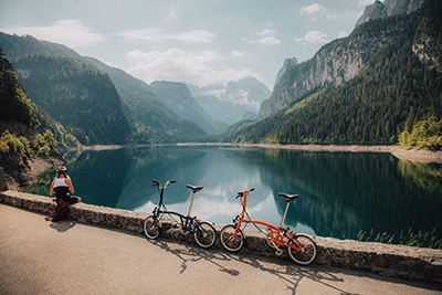 Two Bromptons are leaning against a bridge overlooking a beautiful lake