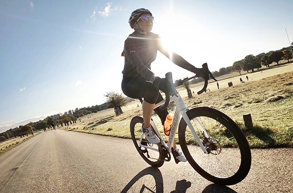 Louisa Holbrook wearing helmet and sunglasses and riding a bike outside