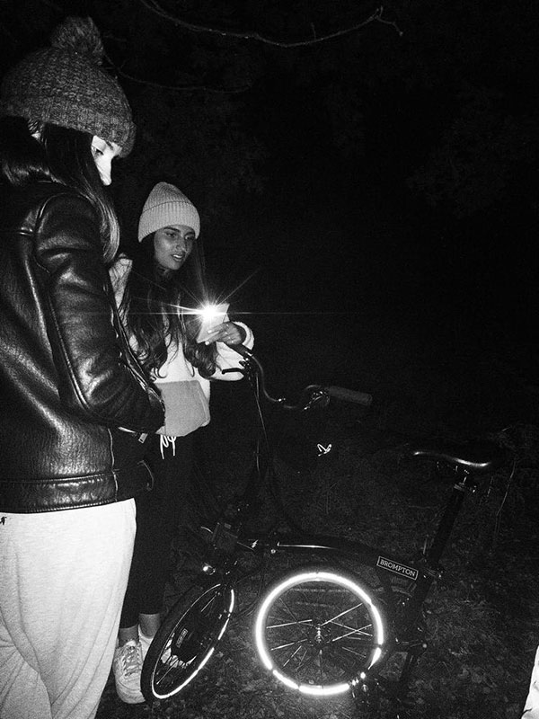 Juliet Oman and Sarah Amer with a Brompton at night time on a group camping trip