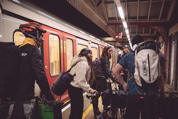 Group of Brompton employees with Brompton Electric Bikes by a London Underground tube