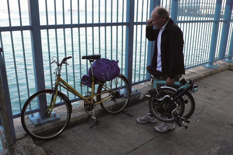 Heinz Stucke with a folded Brompton by railings and water